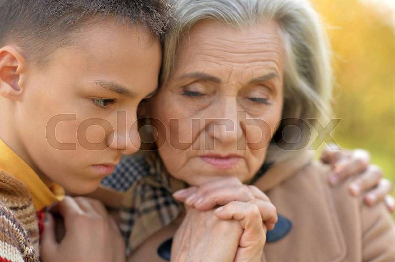Sad grandmother and grandson hugging in park, stock photo