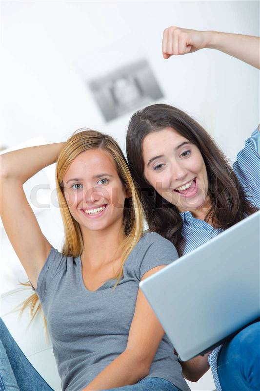 Two female friends on a laptop computer having online success, stock photo