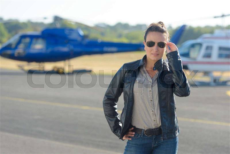 Pretty pilot woman on helicopter background, stock photo