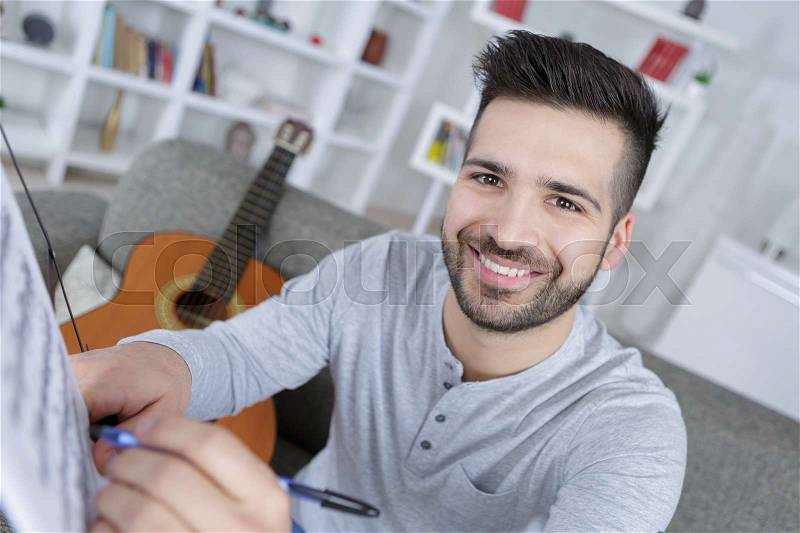 Writing a song for guitar playing, stock photo