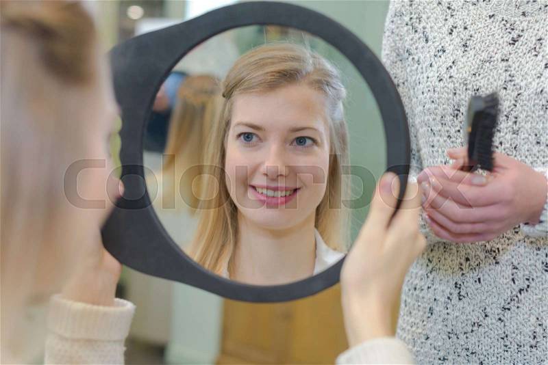 Satisfied girl customer looking at herself on the mirror, stock photo