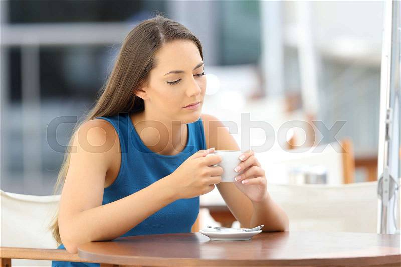 Single pensive and sad lady sitting in a coffee shop terrace, stock photo