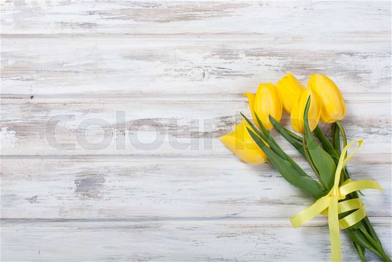 Bouquet of yellow tulips and gift box with yellow ribbon on vintage white wooden table background. holidays concept. Copy space. , stock photo