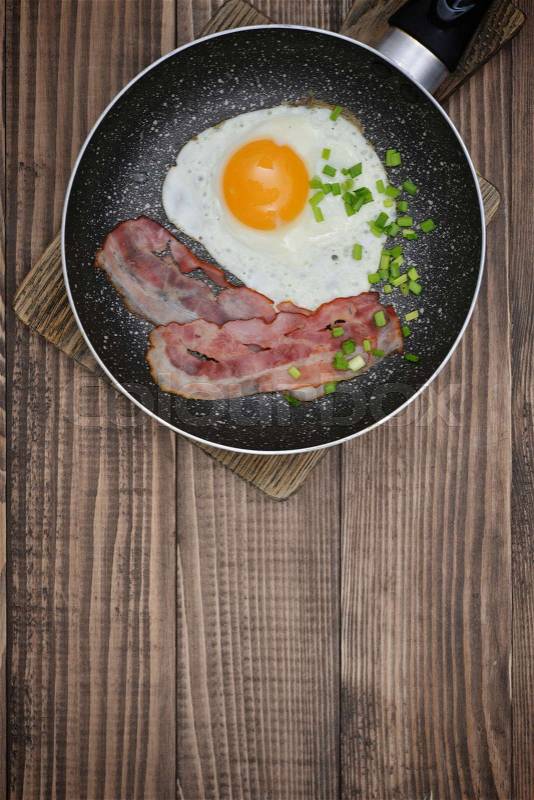 Bacon with sunny side up egg on pan closeup top view, stock photo