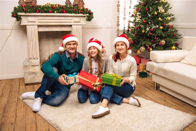 Happy family holding christmas gifts and smiling at camera at home , stock photo