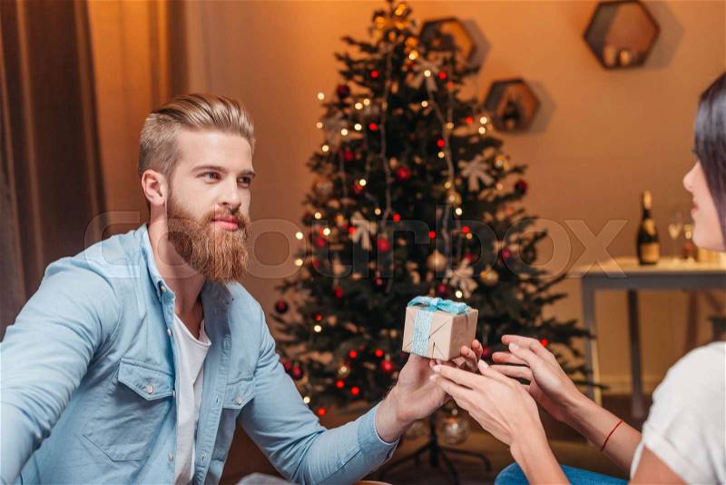 Handsome bearded man presenting christmas gift to girlfriend , stock photo