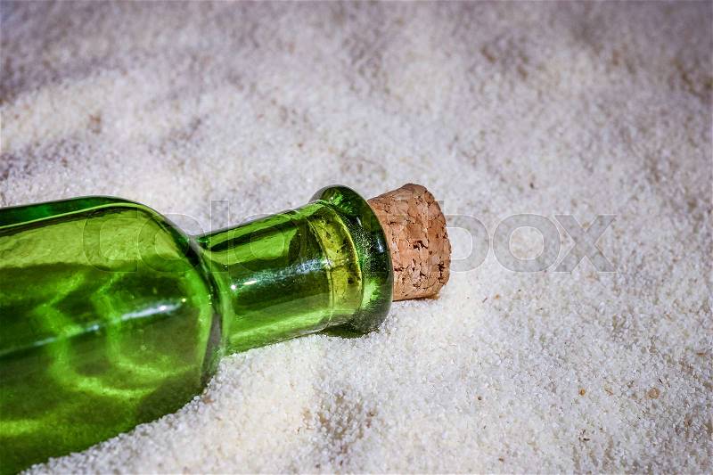 A beautiful green bottle in the sand, stock photo