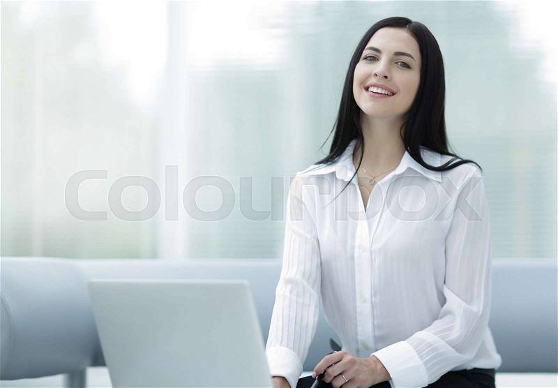 Portrait of a successful young woman sitting at a desk on a blurred background. . business concept. business background, stock photo