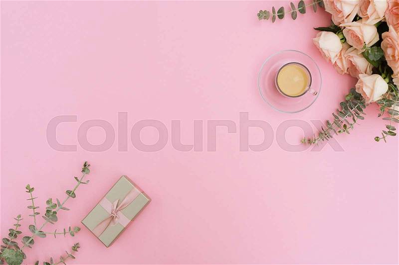 Cup of coffee with gift or present box and flowers on pink table from above, flat lay frame, stock photo