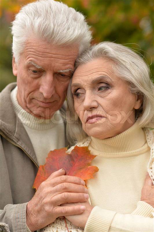 Portrait of sad senior couple hugging outdoors, stock photo