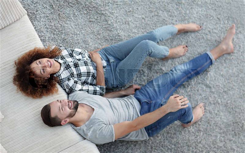 View from above newlyweds lying on the carpet in a new apartment, stock photo