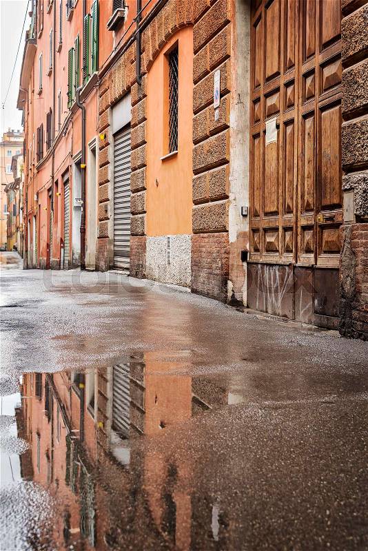 Image of Bologna back street buildings refleced in rain puddle. , stock photo