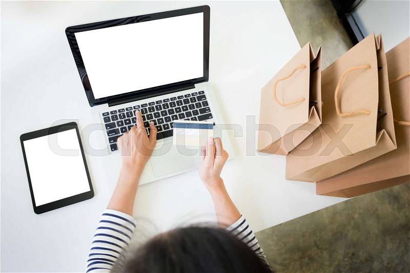 Closeup of happy young woman holding credit card inputting card information while and using laptop computer at home. Online shopping concept, stock photo