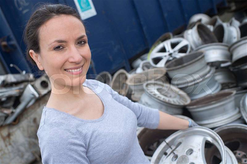 Happy mechanic woman with tyres on background, stock photo