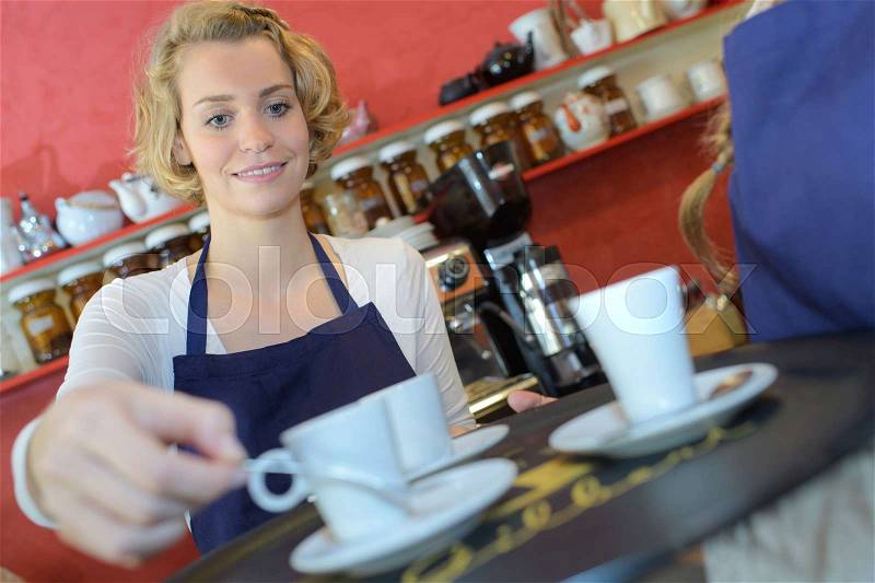 Woman serving tea at a coffee shop, stock photo