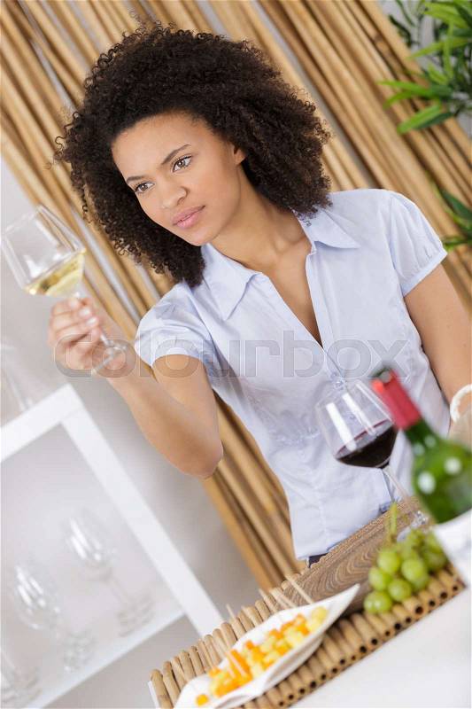 Attractive woman tasting wine while sitting in restaurant, stock photo
