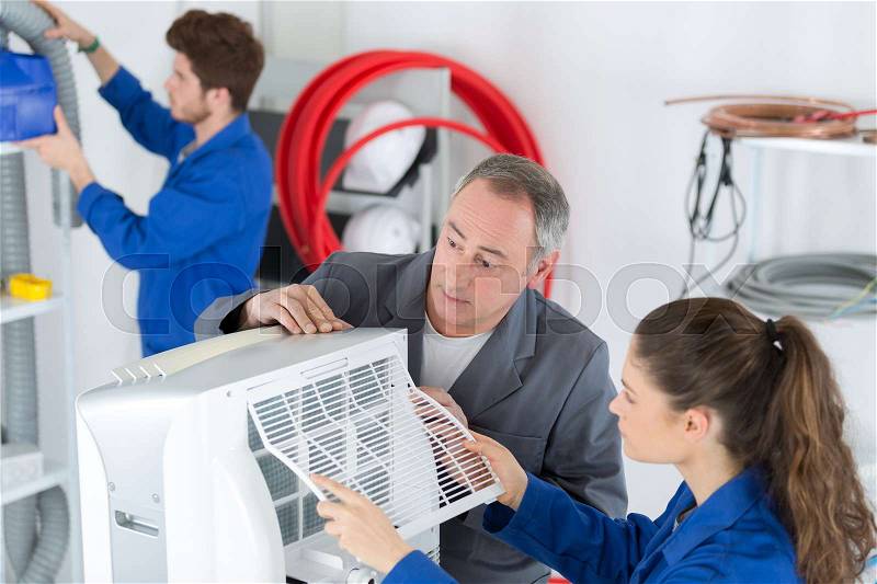 Technicians repairing an industrial air conditioning compressor, stock photo
