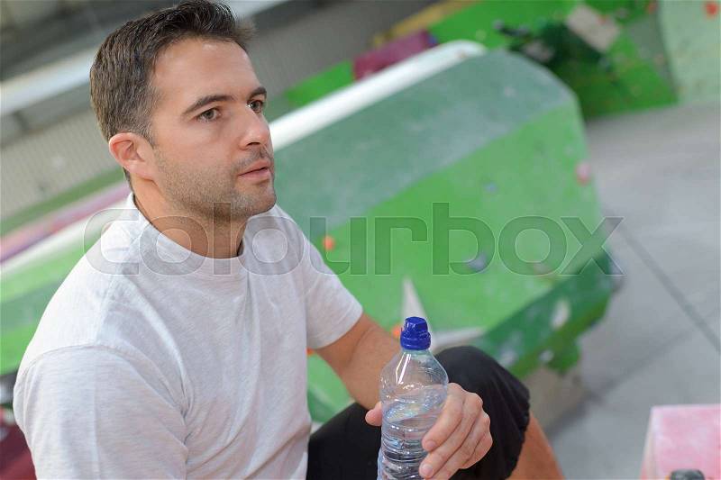Young fit man having a break between climbing sessions, stock photo