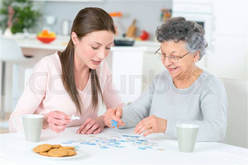Grand daughter and grand mother working on puzzle, stock photo