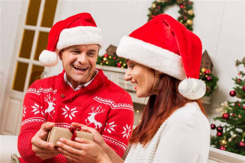 Handsome mature man giving christmas present to wife, stock photo