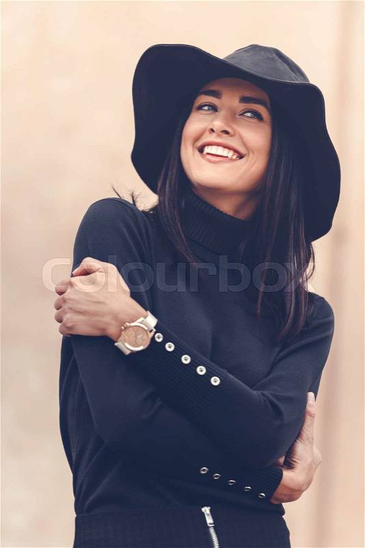 Beautiful woman in black clothing with hat posing outdoors, stock photo