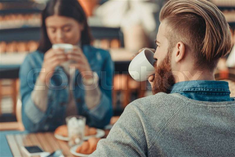 Young couple drinking coffee in cafe outdoors, stock photo