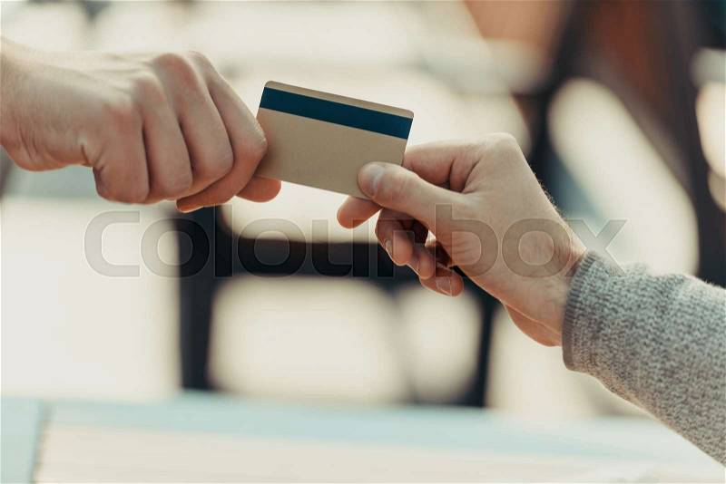 Cropped shot of woman giving credit card to man for purchase, stock photo