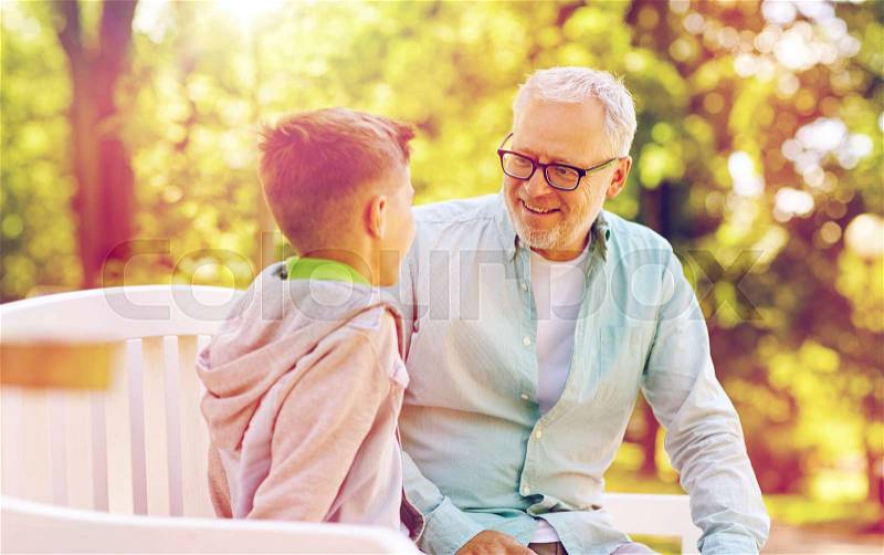 Family, generation, communication and people concept - happy grandfather and grandson talking at summer park, stock photo