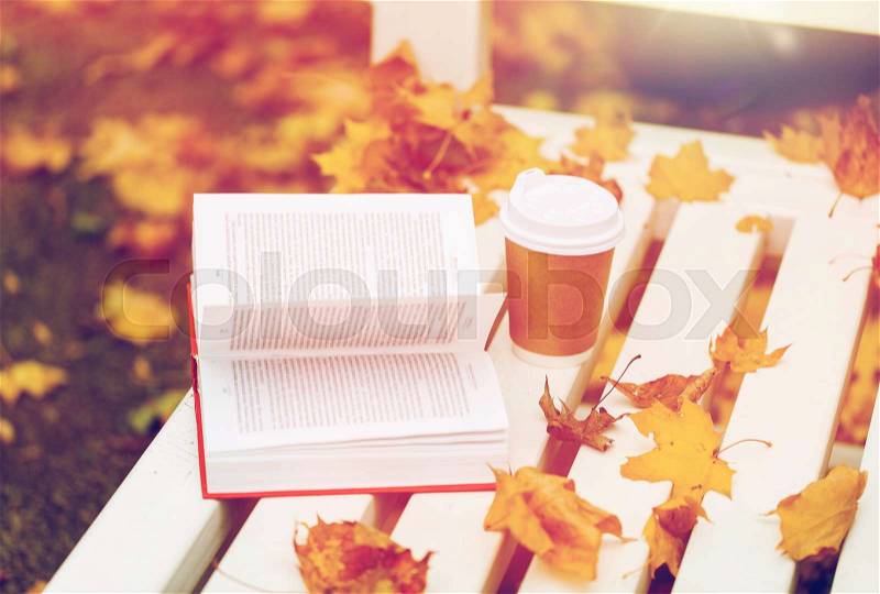 Season, education and literature concept - open book and coffee cup on bench in autumn park, stock photo