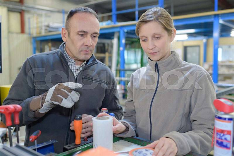 Explaining tack in factory to new employee, stock photo