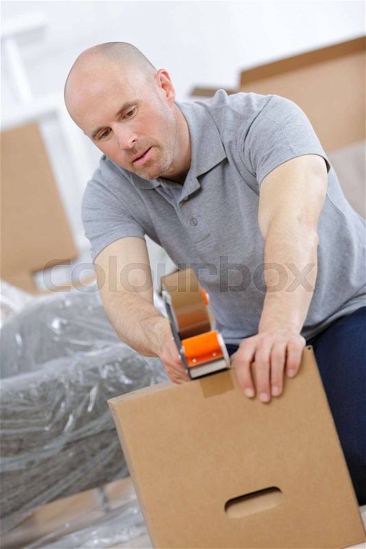 Man packing things and taping boxes, stock photo