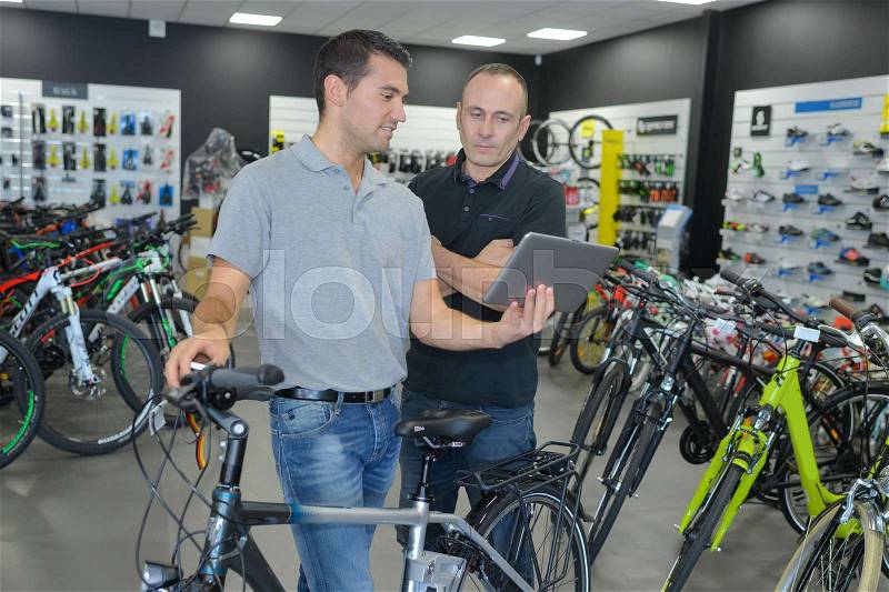 Happy smiling man choosing a bike while comparing price online, stock photo