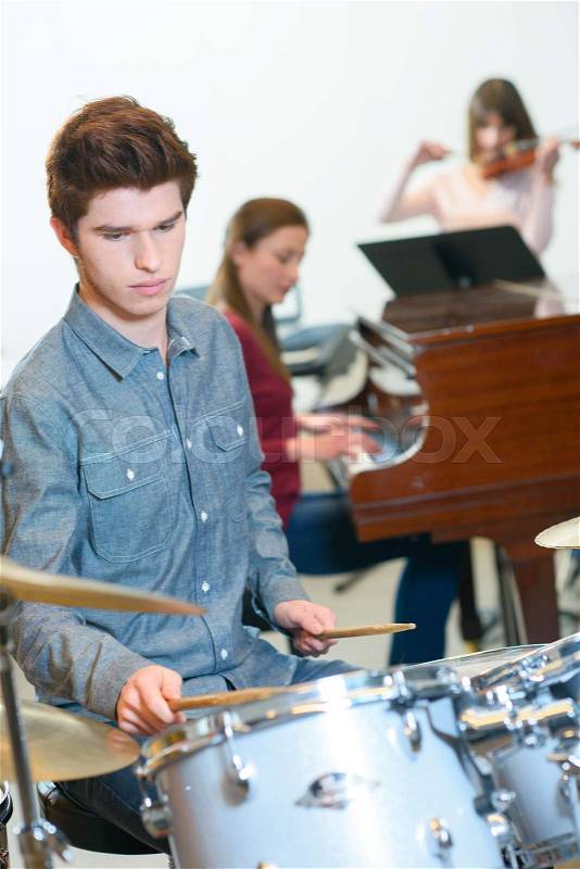 Young drummer with drumsticks in a music class, stock photo