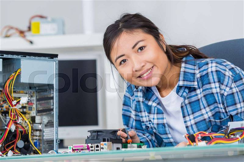 Woman repairing an electronic component of a computer, stock photo