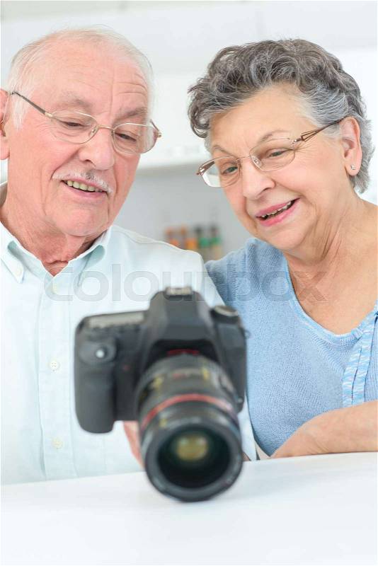Old couple looking on camera screen with pictures, stock photo