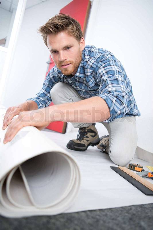 Man rolling out floor covering, stock photo