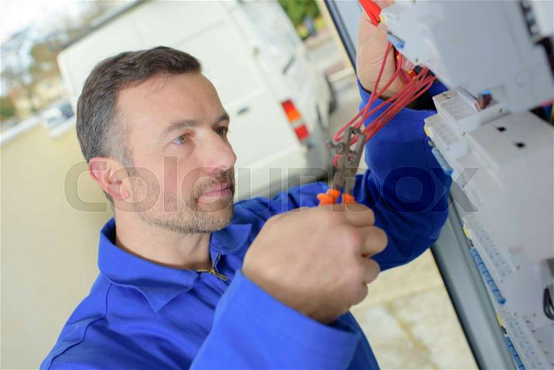 Electrician cuts wire with pliers, stock photo