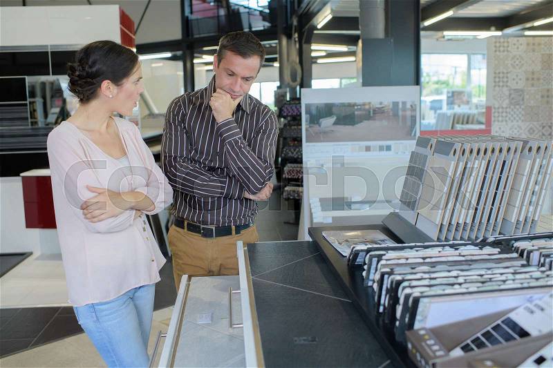 Happy couple choosing tile for bathroom in store, stock photo