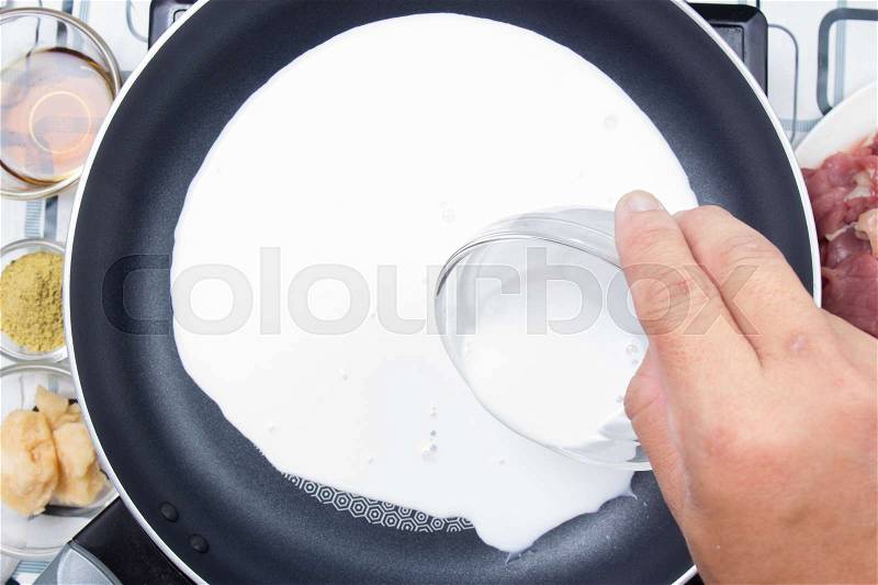 Chef pouring coconut milk to the pan / Cooking green curry concept, stock photo