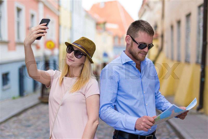 Travel and tourism concept - man with city map and woman taking selfie photo with smart phone, stock photo