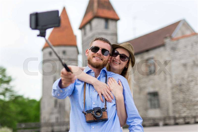 Travel concept - happy tourists taking photo with smart phone on selfie stick, stock photo