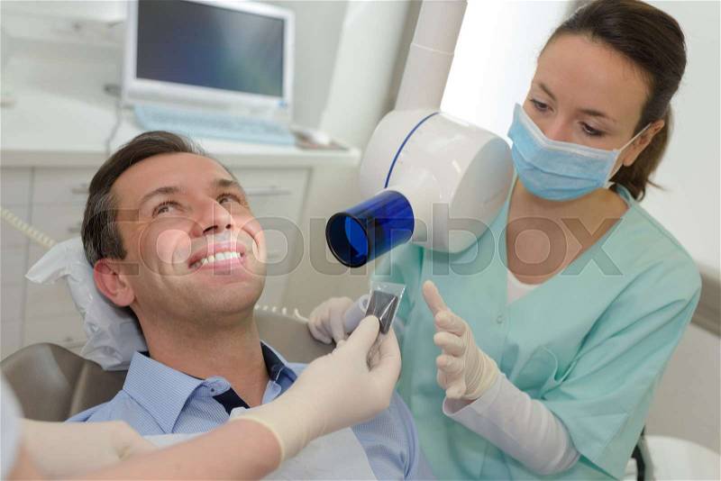 Female dentist with male patient at dental office, stock photo
