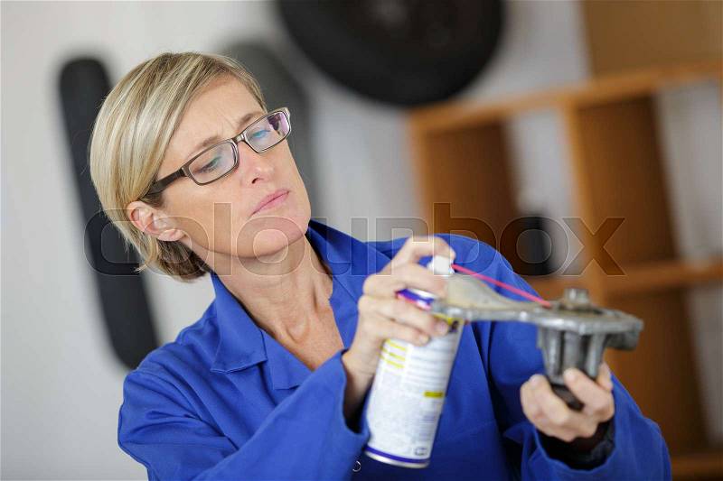 Auto mechanic woman lubricating auto part, stock photo