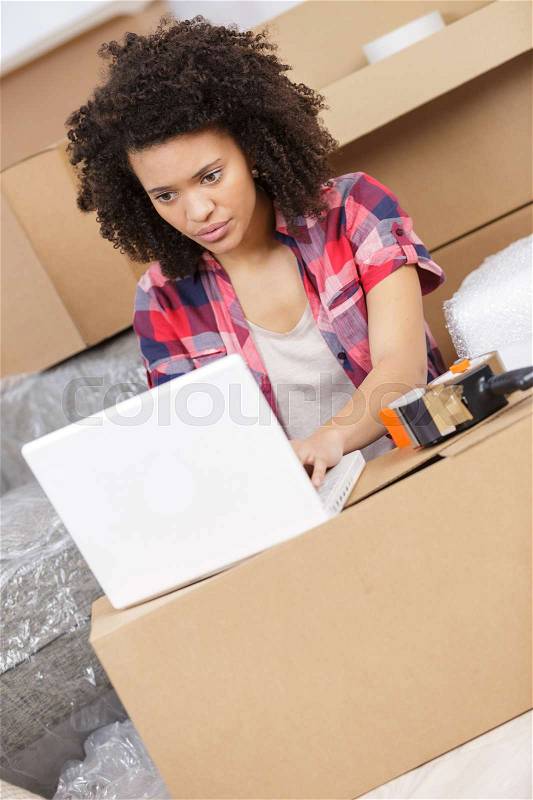 Beautiful woman working with a laptop during office relocation, stock photo