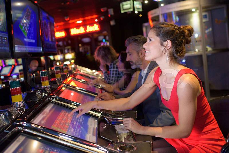 Cheerful pretty woman playing slot machines in casino, stock photo