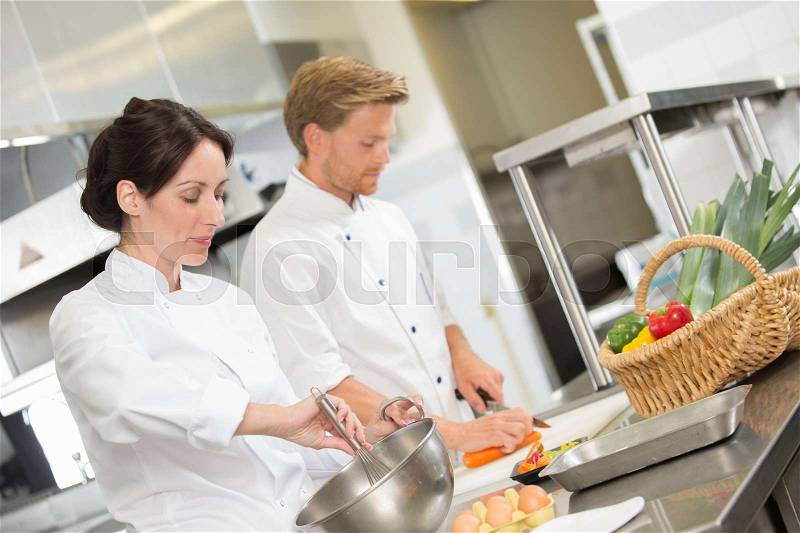 Positive professional chef and cook working at restaurant kitchen, stock photo