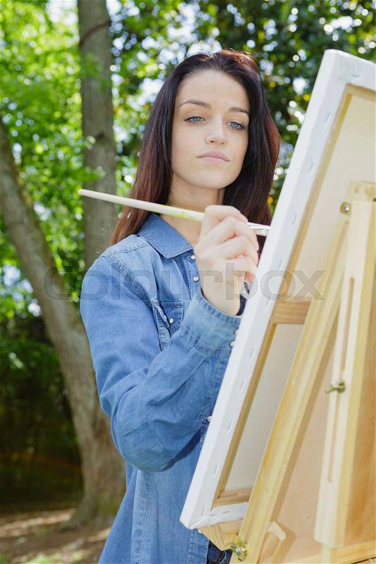 Young lovely caucasian woman painting outdoors, stock photo