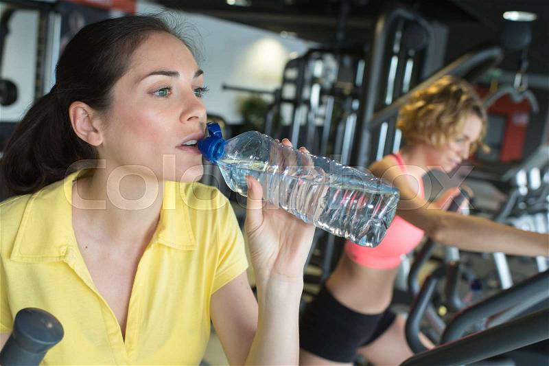 Beautiful girl drinking water in the gym after long training, stock photo