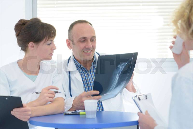 Doctor and nurses reviewing xray during coffee break, stock photo