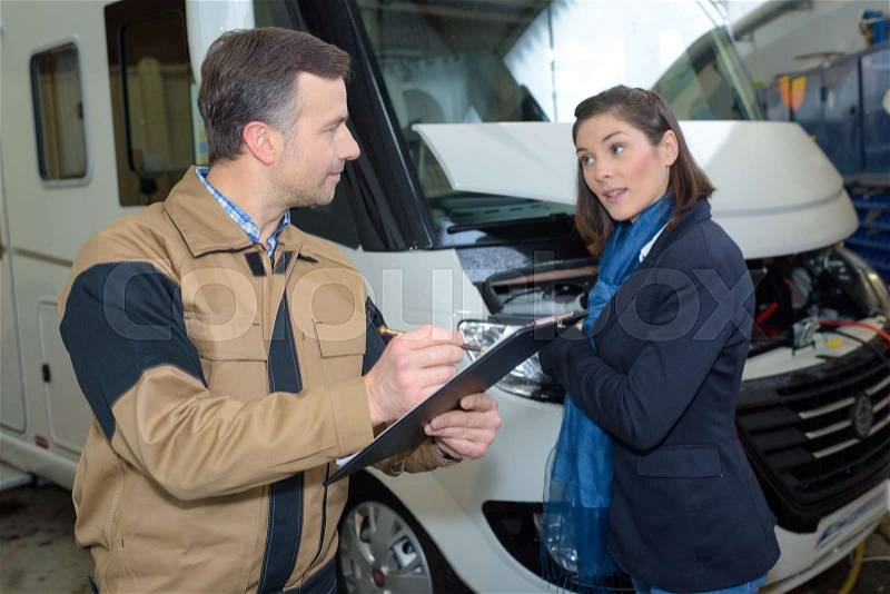 Rental company agent and female customer reviewing camper, stock photo